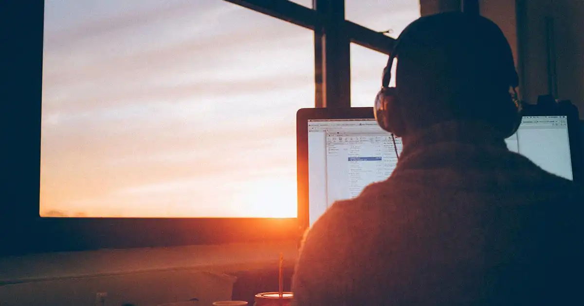 Man at sunset near window using computer
